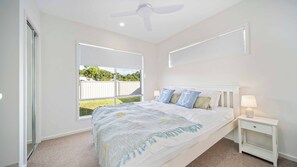 A bedroom with a bed, a nightstand, a ceiling fan, and a window with a view of a fenced yard. - Tuckeroo Retreat -Peaceful home in Mullumbimby - views of Mt Chincogan (Mullumbimby)