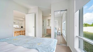 A bedroom with a large bed, a bathroom with a glass shower door, and a view of a backyard through a window. - Tuckeroo Retreat -Peaceful home in Mullumbimby - views of Mt Chincogan (Mullumbimby)