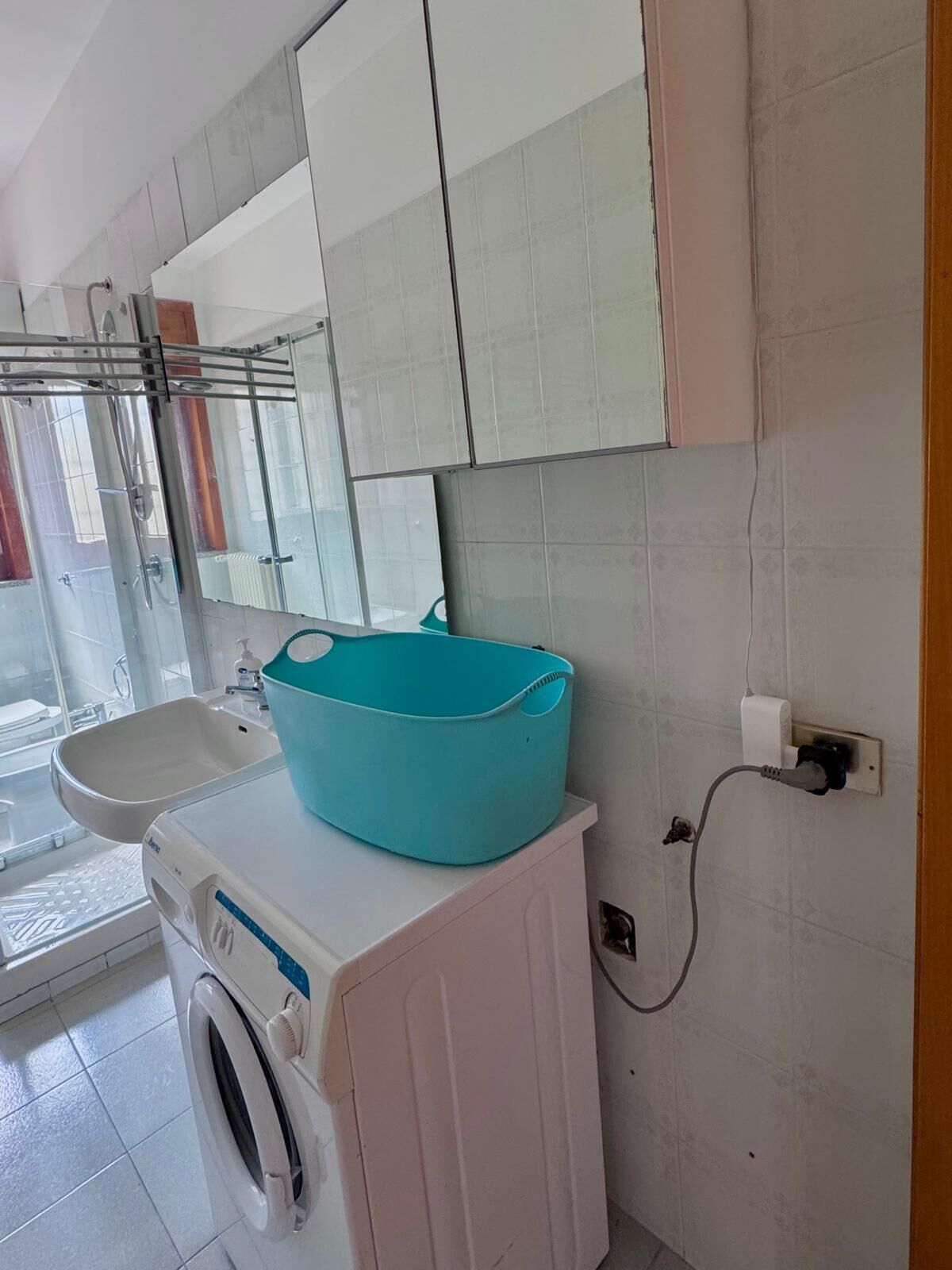 Ein Badezimmer mit einer Waschmaschine, einem Waschbecken und einem großen Spiegel über dem Spiegelschrank.