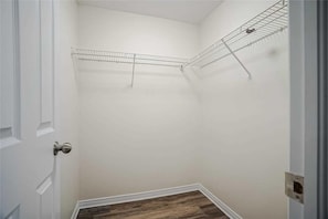 A room with a white door, a corner shelf unit, and a wooden floor. - Luxe Chicopee Townhome: Ravine Forrest, Sleeps 8 (Kitchener)