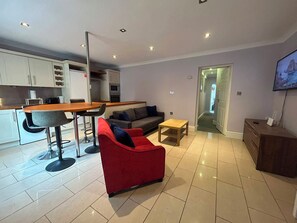A modern living room with a red sofa, a wooden coffee table, and a kitchen area with a dining table and chairs. - Characterful 2BDR Cottage Flat with Terrace Dublin (Dublin)