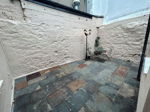 A courtyard with a brick wall, a metal table with chairs, and a street lamp.