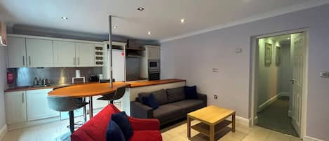 A compact living space with a kitchenette, a dining area, a sofa, and a small table.