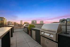 An outdoor rooftop bar with a grill and seating area, overlooking a cityscape. - Boulevard Stays River North Retreat Near Magnificent Mile 01 (Chicago)