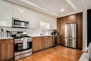 A modern kitchen with stainless steel appliances, wooden cabinets, and a wooden floor. - Boulevard Stays River North Retreat Near Magnificent Mile 01 (Chicago)