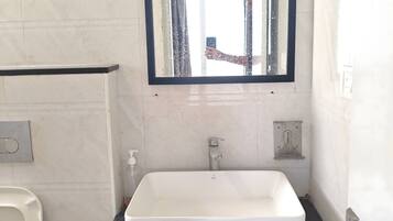 A bathroom with a white sink, a mirror, and a toilet.