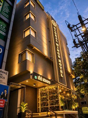 Un hotel con un letrero llamativo que dice 'GLOBAL WINDS HOTEL' y un letrero del restaurante 'DESI MASALA'.