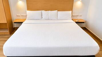 A neatly made bed with a wooden headboard, two bedside tables, and wall-mounted lights.