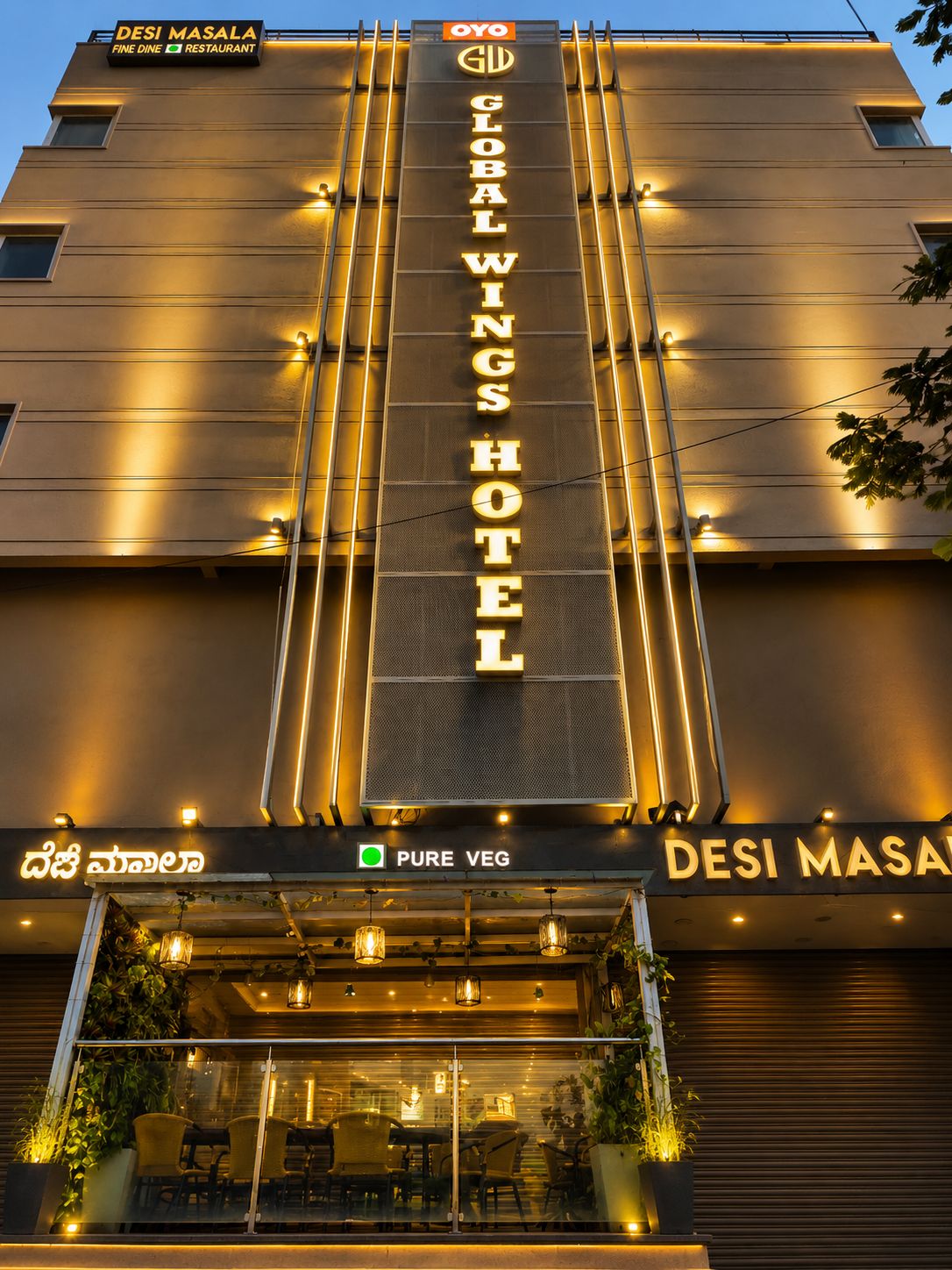 A hotel with a prominent sign reading 'DESI MASALA FINE DINE RESTAURANT' and 'GLOBAL WINGS HOTEL'.