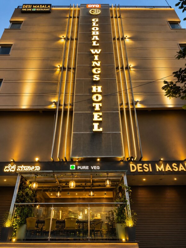 A hotel with a prominent sign reading 'DESI MASALA FINE DINE RESTAURANT' and 'GLOBAL WINGS HOTEL'.