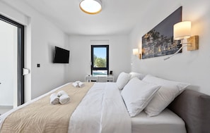 A hotel room with a bed, a desk, a chair, a TV, and a painting on the wall. - Gorgeous home in Dubrava Kod Sibenika with sauna (Dubrava Kod Sibenika)