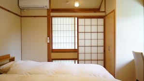 Quarto japonês tradicional com cama, portas deslizantes shoji e ar-condicionado instalado no teto.