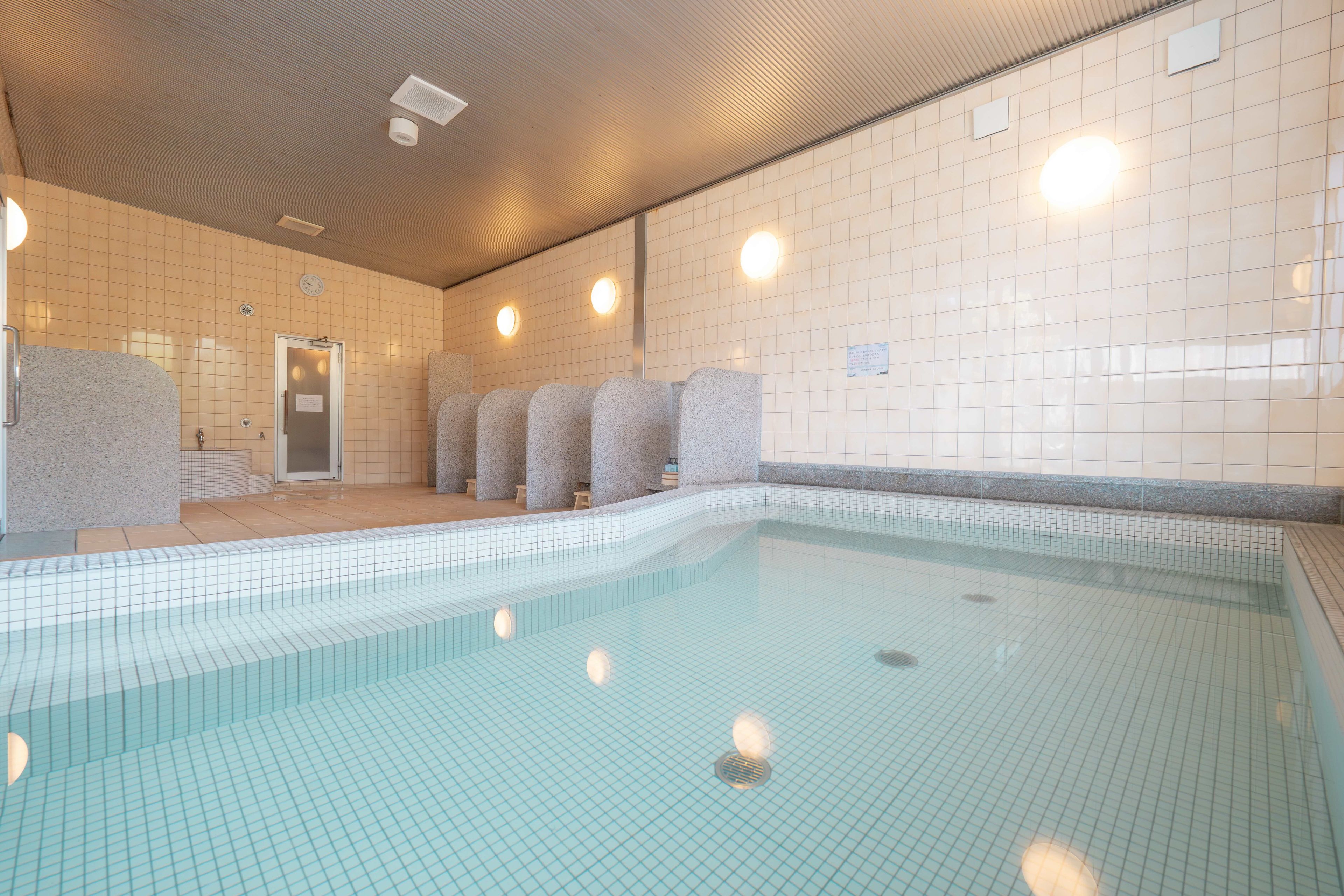 Una piscina con paredes de azulejos e iluminación empotrada en el techo.