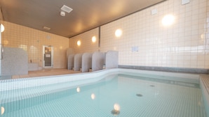 Piscina com paredes revestidas e teto com iluminação embutida.