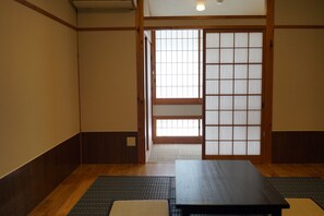 Una habitación japonesa tradicional con suelo de tatami, puertas correderas shoji y una mesa de madera baja.