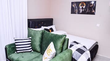 Un dormitorio con una cama, un sofá verde y un cuadro en la pared.