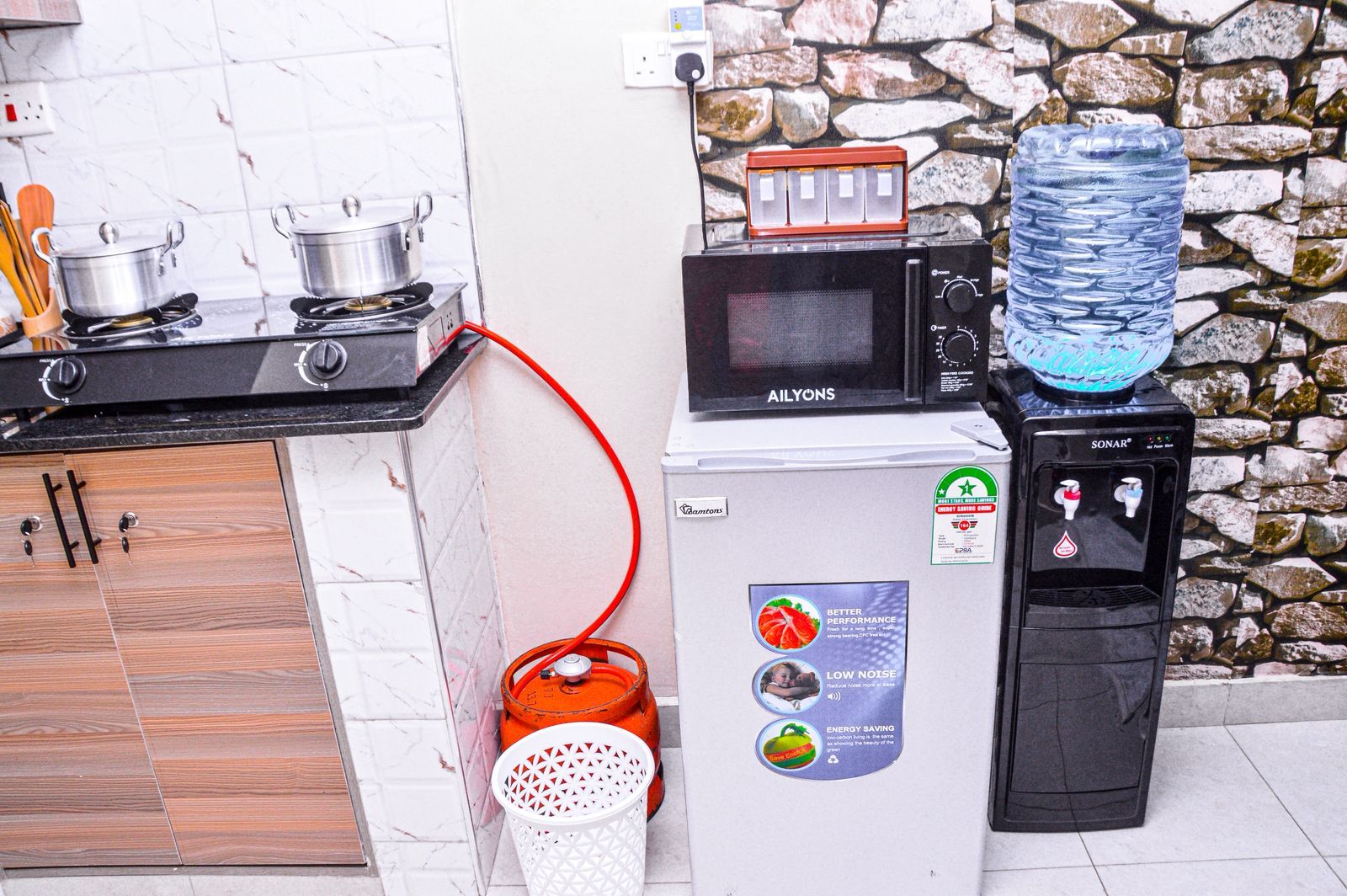 Cozinha equipada com micro-ondas, bebedouro e fogão a gás.