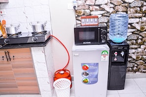 Una cocina equipada con microondas, dispensador de agua y estufa a gas.