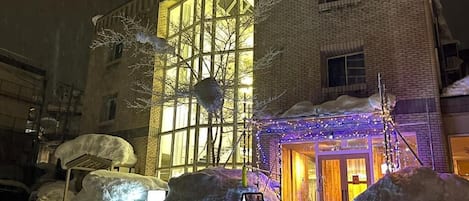 Un edificio con un amplio ventanal y una entrada cubierta de nieve.