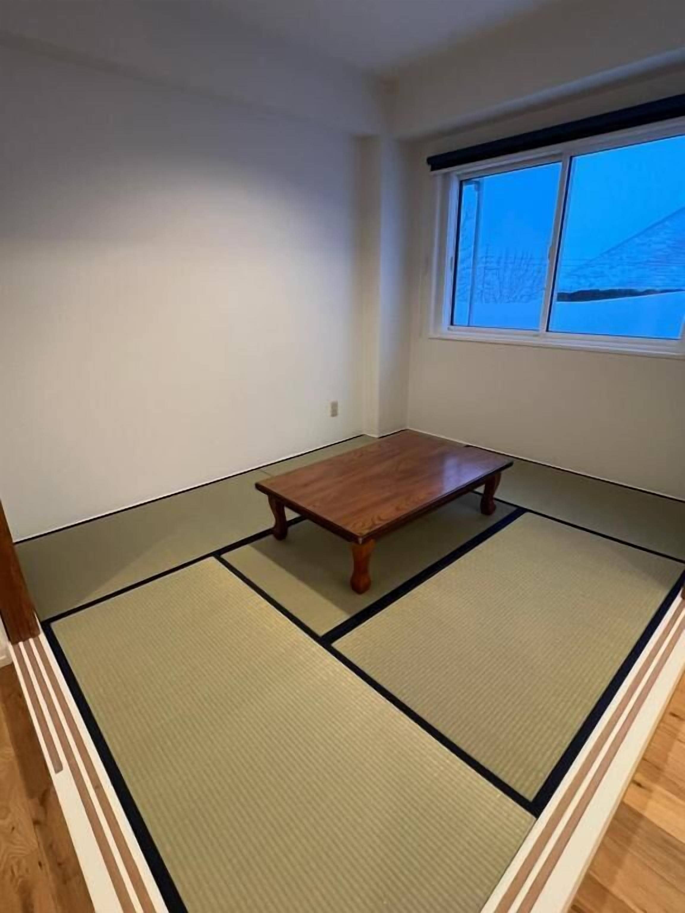 Une pièce avec des tatamis, une table en bois et une fenêtre donnant sur un beau paysage.