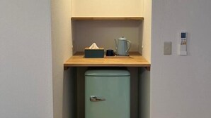 Una kitchenette compacta con un refrigerador pequeño, una encimera de madera y una lámpara.