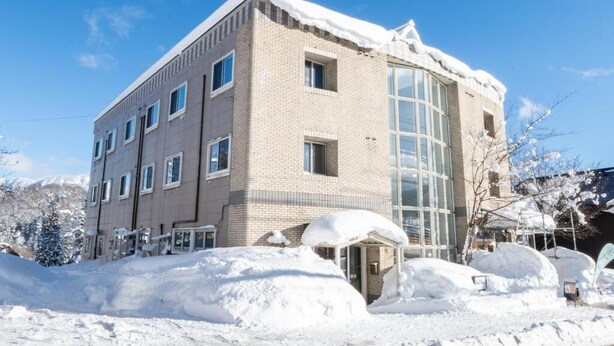 Un edificio de varios pisos con fachada de ladrillo y grandes ventanales, rodeado de nieve.