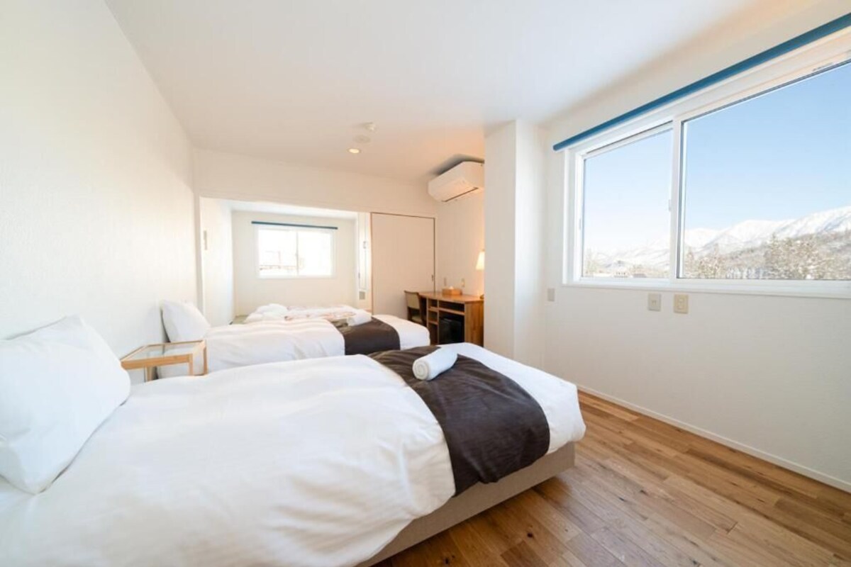 Ett hotellrum med två sängar, ett skrivbord och ett stort fönster med utsikt över bergen.