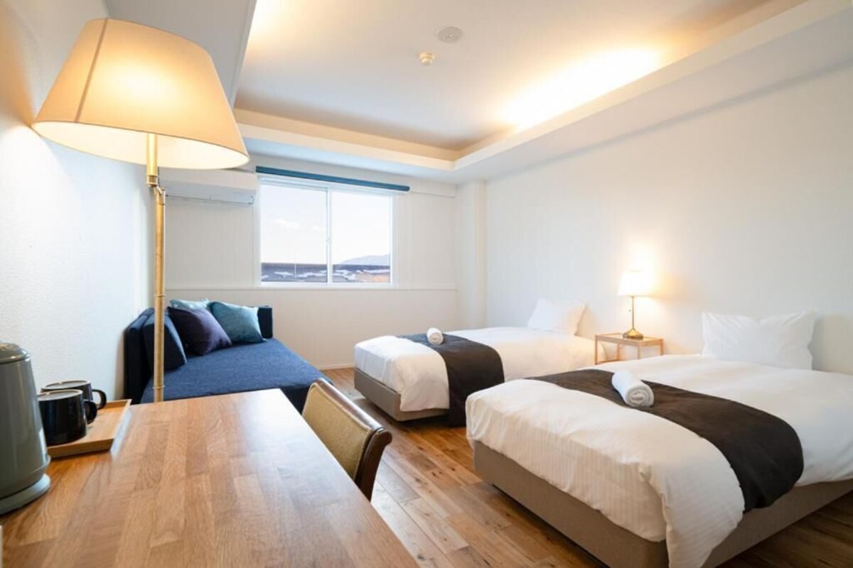 Ett hotellrum med två sängar, ett skrivbord, en lampa och utsikt över omgivningarna.