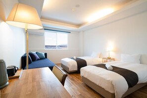 Ett hotellrum med två sängar, ett skrivbord, en lampa och utsikt över omgivningarna.