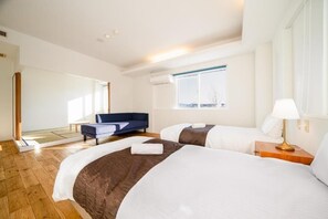 Ett hotellrum med två sängar, en soffa, ett fönster och en lampa.