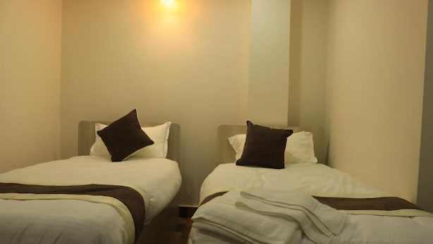 Hotellihuone, jossa on kaksi erillistä sänkyä, ja jokaisessa sängyssä on tyyny ja peitto.