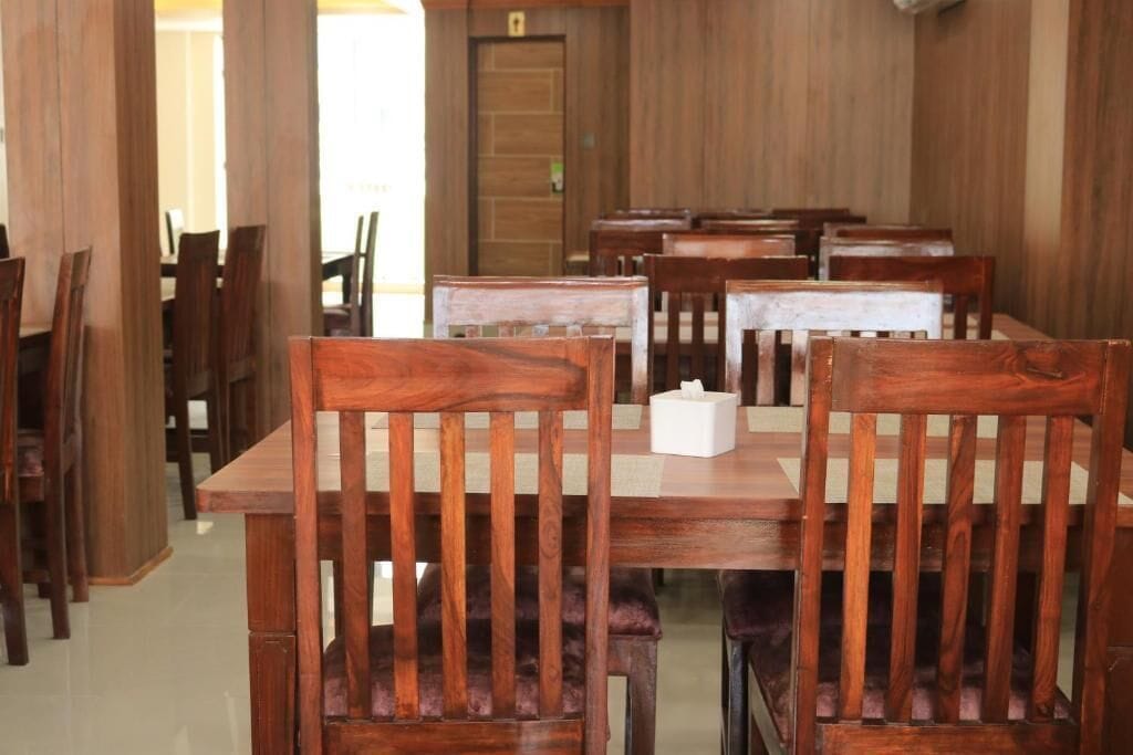 A dining area with wooden tables and chairs, a door in the background, and a white object on one table.
