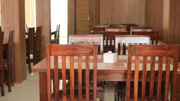 A dining area with wooden tables and chairs, a door in the background, and a white object on one table.