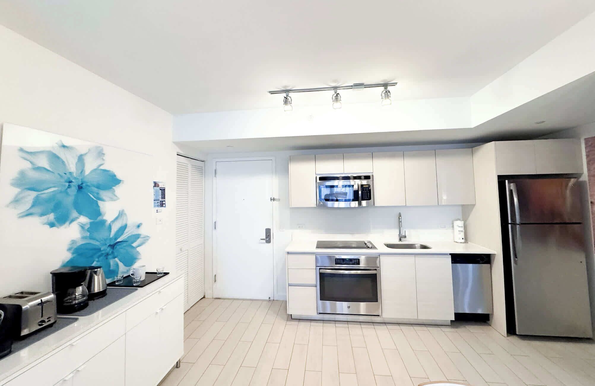 Una cocina moderna con armarios blancos, un refrigerador de acero inoxidable, un microondas y un horno.