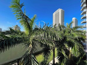 Un edificio moderno e imponente, circondato da palme sotto un cielo azzurro limpido.
