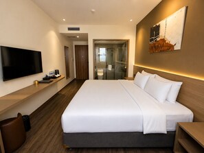 A modern hotel room with a large bed, a flat-screen TV, and a glass-enclosed shower area. - Chu Gia Hotel Mong Cai (Mong Cai)