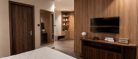 Habitación de hotel con una cama, televisión, armario de madera y un estante con objetos.