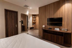 Habitación de hotel con una cama, televisión, armario de madera y un estante con objetos.