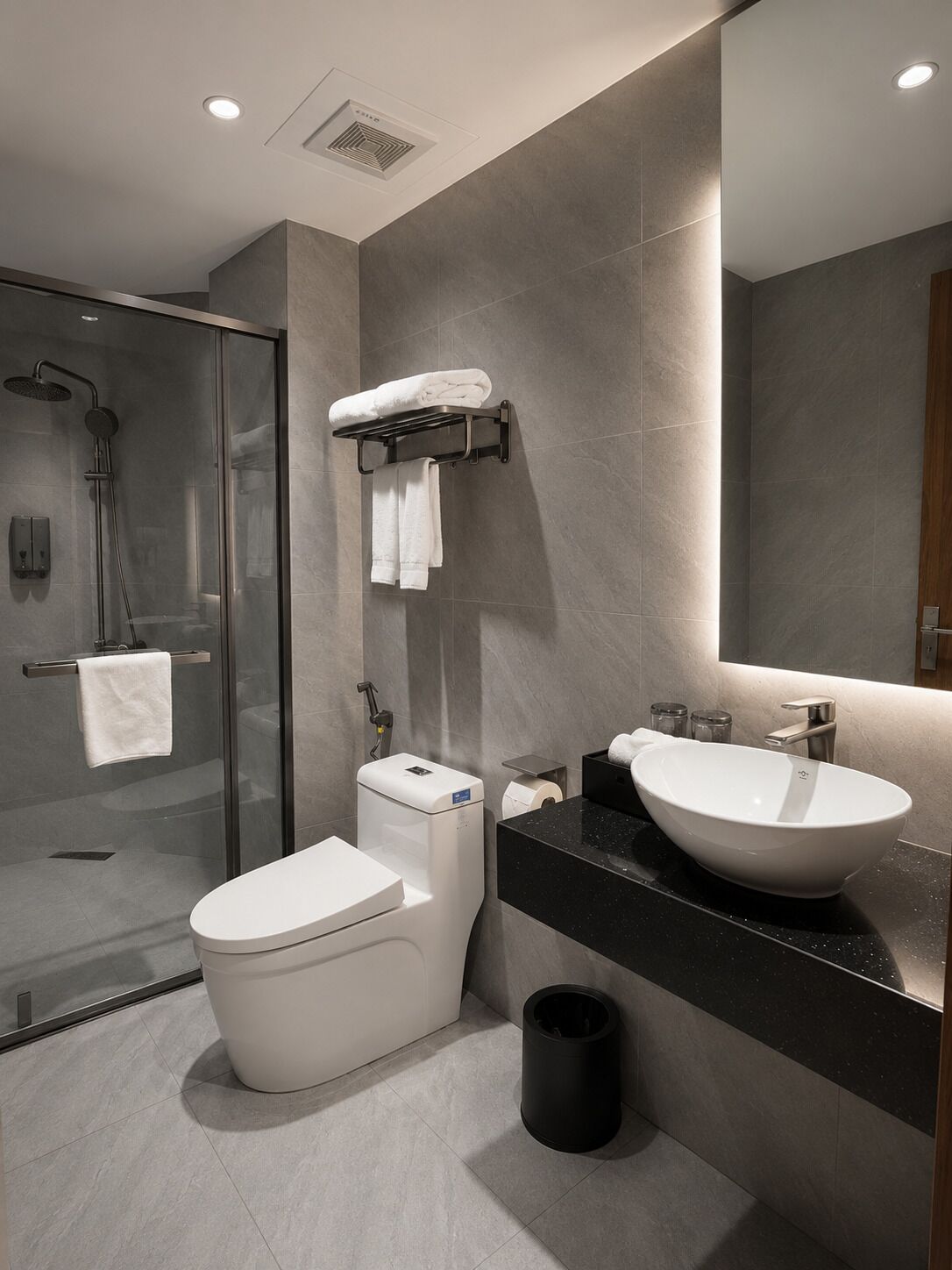 Un baño moderno con ducha de vidrio, inodoro, lavabo y espejo.