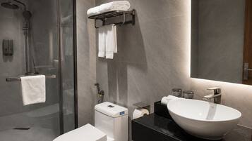 Un baño moderno con ducha de vidrio, inodoro, lavabo y espejo.