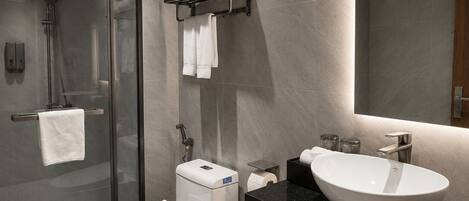 A modern bathroom with a glass-enclosed shower, a toilet, a sink, and a mirror.