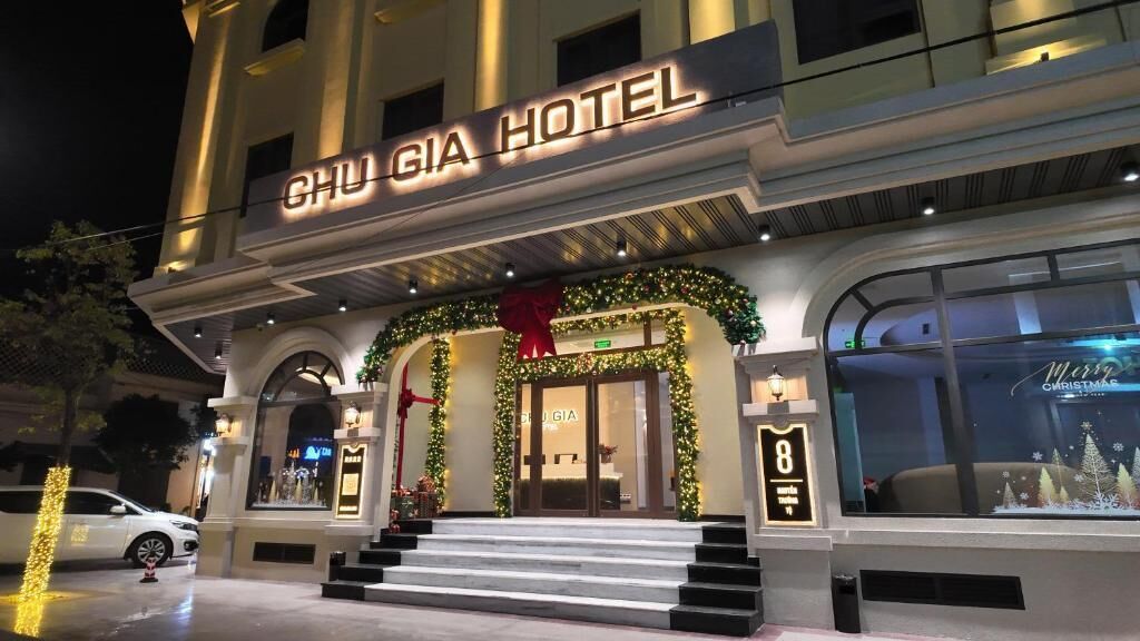 A hotel entrance with a sign reading 'CHU GIA HOTEL,' a set of stairs leading up to the door, and a Christmas tree decoration.