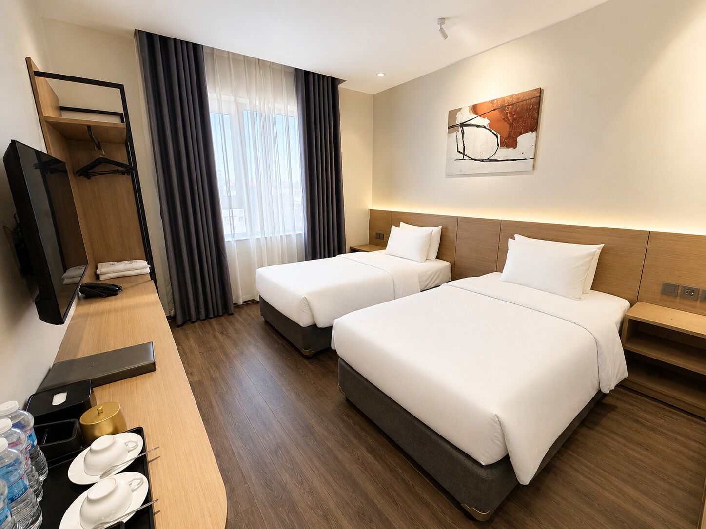 Habitación de hotel con dos camas, un escritorio con espejo, televisor y ventana con cortinas.