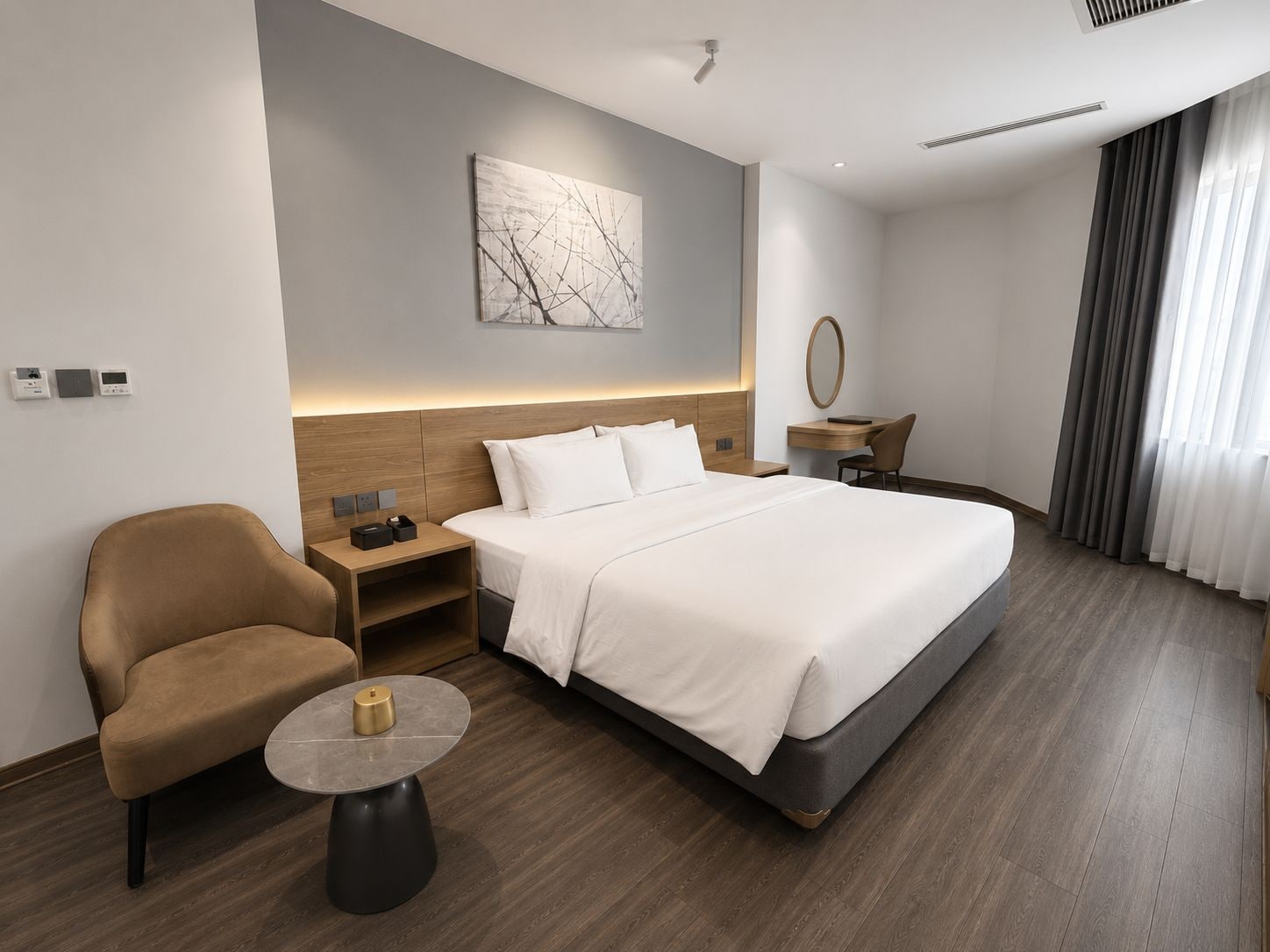 A modern hotel room with a large bed, a desk, a chair, and a small table.