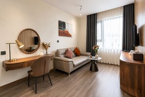 A modern hotel room with a wooden desk, a sofa, a coffee table, and a television. - Chu Gia Hotel Mong Cai (Mong Cai)