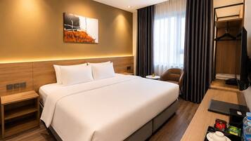 Quarto de hotel com cama grande, mesas de cabeceira, escrivaninha com cadeira, televisão e um quadro na parede.