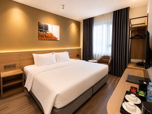 A hotel room with a large bed, bedside tables, a desk with a chair, a television, and a painting on the wall. - Chu Gia Hotel Mong Cai (Mong Cai)