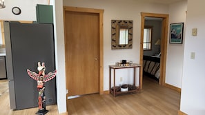 A hallway with a wooden door, a small table with decorative items, and a poster on the wall.
