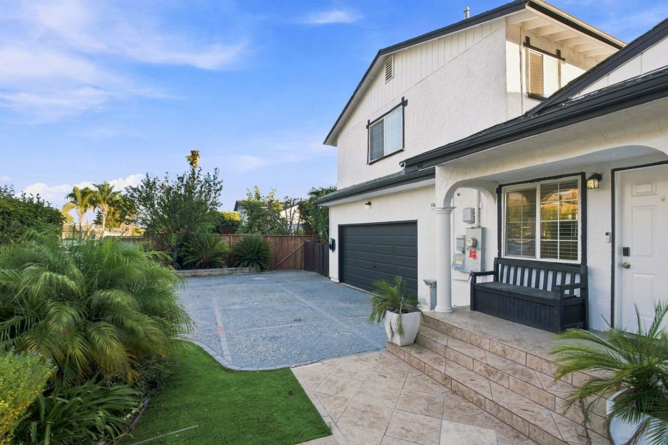 Une maison à deux étages avec un garage, une véranda et une pelouse bien entretenue.