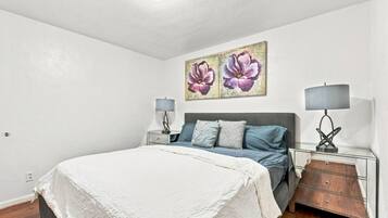 Une chambre à coucher avec un lit, deux tables de chevet, une commode et une lampe fixée au mur.
